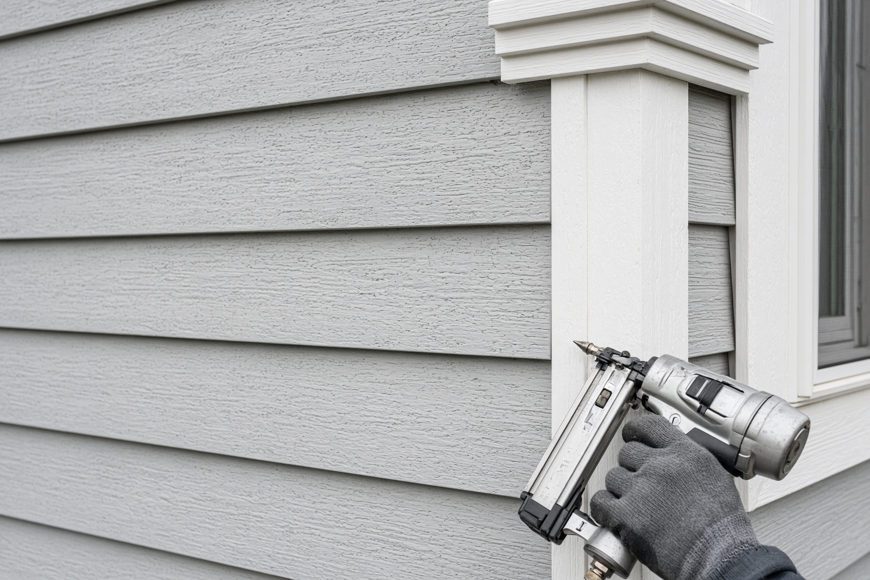 Fiber cement lap siding being fastened at a corner